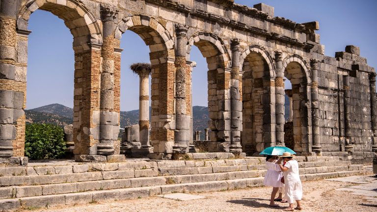 Tourists walk through the ruins of the ancient Roman site of Volubilis, near the town of Moulay Idriss Zerhounon in Morocco's north central Meknes region, on July 25, 2018. - Situated in the centre of a fertile plain at the foot of Mount Zerhoun, the towering remains of Morocco's oldest Roman site, Volubilis, were long neglected.
But after decades of looting and decay, custodians of the now closely guarded ancient city are turning the page and attracting back tourists. (Photo by FADEL SENNA / AFP)        (Photo credit should read FADEL SENNA/AFP via Getty Images)